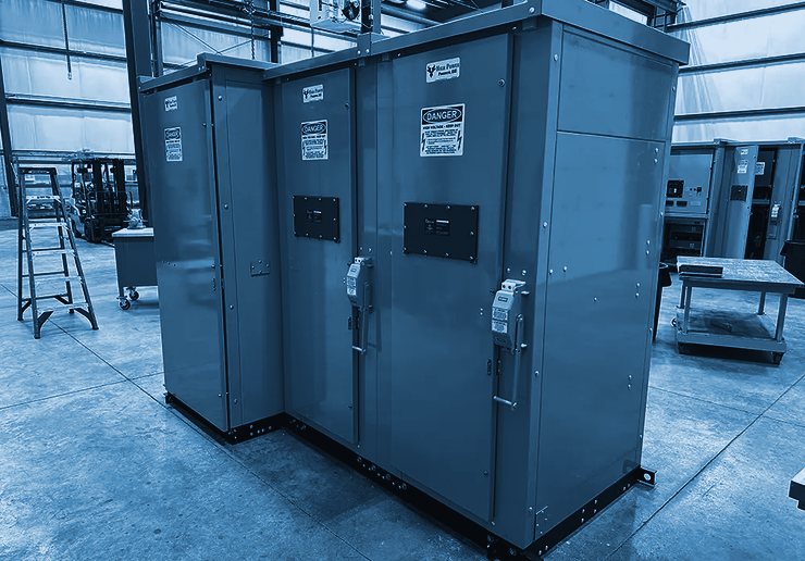 Medium-voltage switchgear assembly with hinged doors and high-voltage warning labels on a shop floor