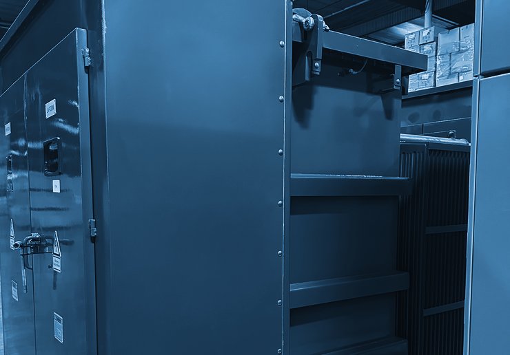 Pad-mount transformer with live-front compartment doors and radiators, on a shipping skid in a warehouse